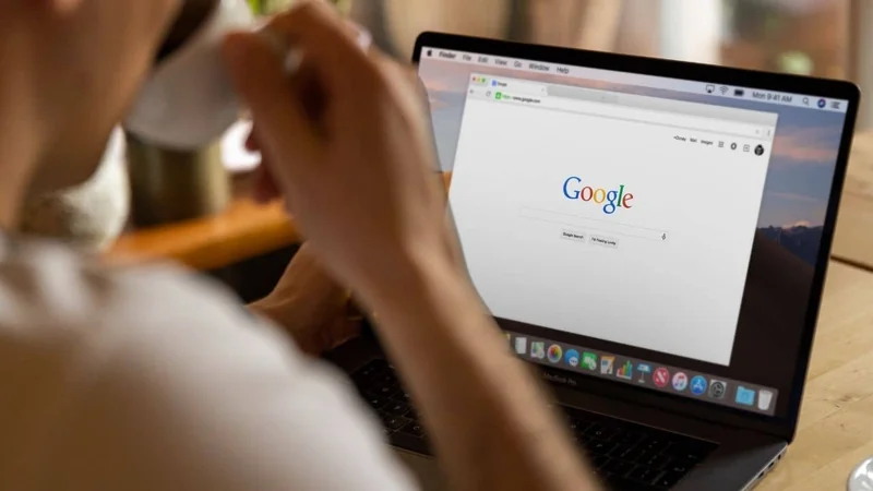 pessoa tomando uma xícara de café enquanto realiza uma busca no google